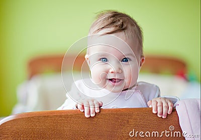 Very cute baby smiles standing in the crib Stock Photo