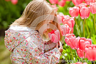 Very cute beautiful girl blonde in pink coat costs around flower Stock Photo