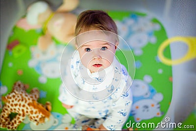 Very cute girl in pajamas sitting in the playpen Stock Photo