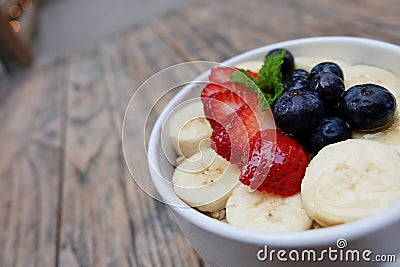 acai bowls with fresh fruit strawberry, blueberry, banana in white bowl on wooden table. Stock Photo