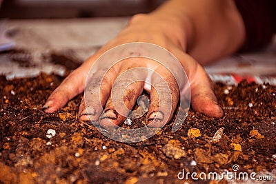 Very dirty female hand with soiled nails stays on the ground, closeup. Stock Photo