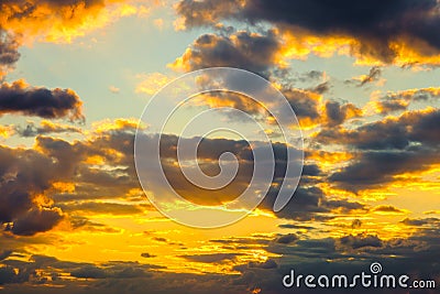 A very dramatic sky full of yellows, blues and oranges. Contrasting clouds during sunset illuminated by the setting sun Stock Photo