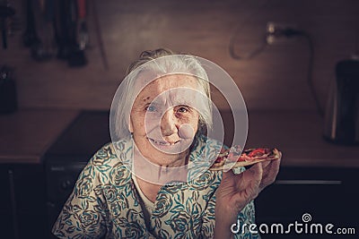 Very elderly woman eating a piece of pizza at home. Stock Photo