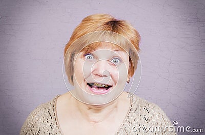 Very emotional woman with gold teeth on a gray background. Stock Photo