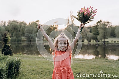 Very happy little girl with her hands up and a bouquet of flowers Stock Photo