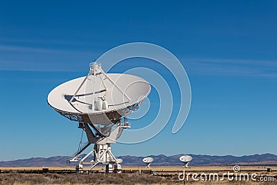 Very Large Array radio antenna dish close with others in distance, blue sky Stock Photo