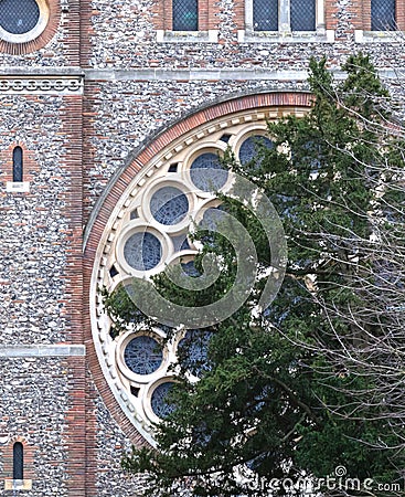 Very large round window in a cathedral, green tree in front of it Stock Photo
