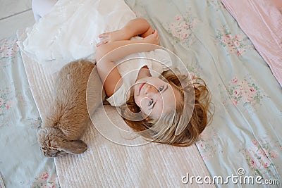 Very nice charming little girl blonde in white dress lying on a Stock Photo