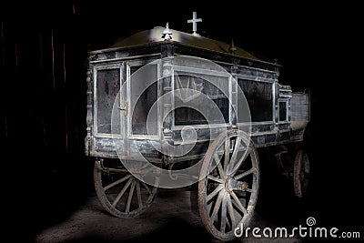 Very old and dusty hearse made of wood with large wooden wheels. Used to transport the coffin with the dead during the funeral in Stock Photo