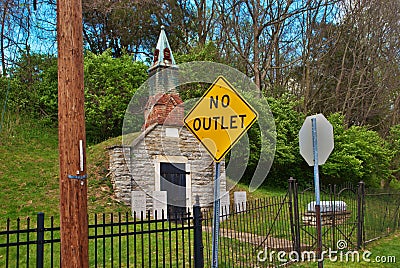 Very old mausoleum built into the side of a hill with steeple, tombstones, wrought iron fence, and no outlet sign Editorial Stock Photo