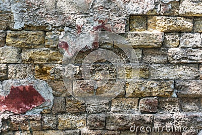 A very old stone wall with fragments of plaster, destroyed over time by weather conditions. Stock Photo