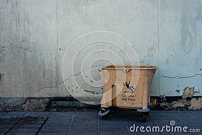 Old Yellow Wringer Bucket near crack old white wall Stock Photo