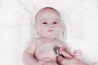 small child, a baby, lies back at the doctor`s office and the doctor listens to the lungs, the heart Stock Photo