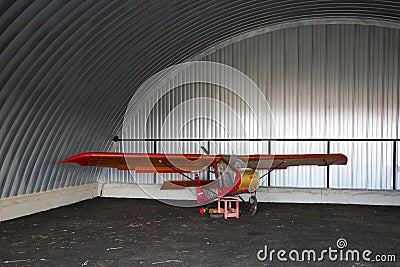 Very small single-place ultralight glider stands in the corner of a metal hangar Stock Photo