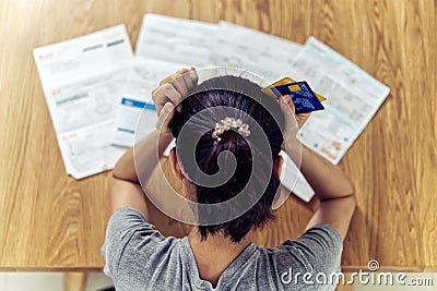 Very stressed young sitting Asian woman hands holding the head worry about find money to pay credit card debt. Stock Photo