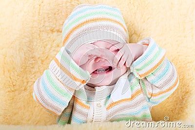 Very tired sleepy baby sitting in a warm sheepskin Stock Photo