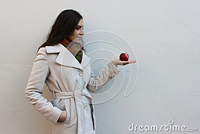 Woman in a coat holds and look a red juicy apple Stock Photo