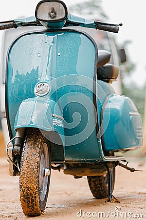 Vespa Scooter front close up view, parked in a muddy road in a rainy day. Sky blue vintage classic motor bike Editorial Stock Photo