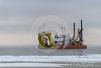 Vessel engaged in dredging at sunset time. Hopper dredger working at sea. Ship excavating material from a water environment Editorial Stock Photo