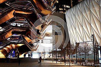 Vessel TKA, a spiral endless staircase with the Shed near it, skyscrappers behind. Night view with bright lights. Hudson Yards Editorial Stock Photo