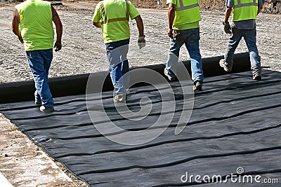 Construction workers unroll a tarpaulin on a new road Editorial Stock Photo