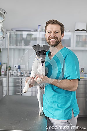 Portrait of smiling veterinary doctor standing with dog at clinic Stock Photo