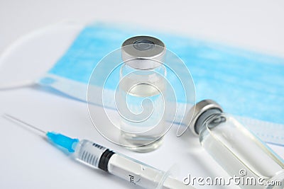 Vials, syringe and surgical mask on background. Vaccination and immunization Stock Photo