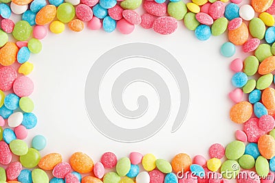 Vibrant candy frame Close up of rainbow colored dragee on white Stock Photo