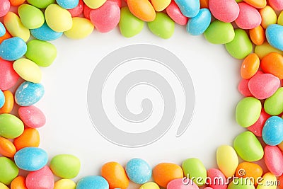 Vibrant candy frame Close up of rainbow colored dragee on white Stock Photo