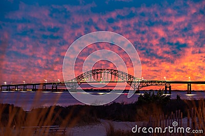 Vibrant colorful sunset sky behind a long steel tied arch bridge. Fire Island New York Stock Photo