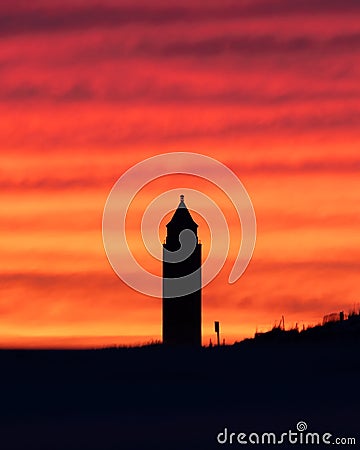 Vibrant colorful sunset sky behind the silhouette of a pencil water tower on the beach. Fire Island Stock Photo