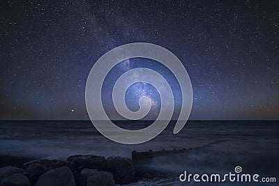 Vibrant Milky Way composite image over landscape of pier at sea Stock Photo