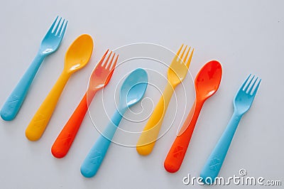 Vibrant multicolored forks, kives and spoons white background Stock Photo