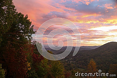 Vibrant colors of the sunrise and changing colors of the fall trees with endless mountains Stock Photo