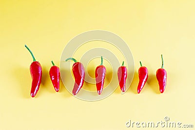 Vibrant red chili on yellow background, lay flat. Red spicy chili peppers wallpaper pattern Stock Photo