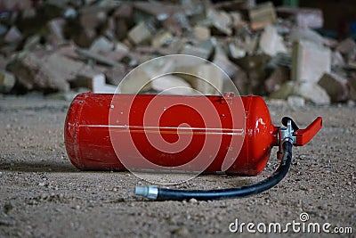 Vibrant red fire extinguisher situated among a pile of grey and white stones Stock Photo
