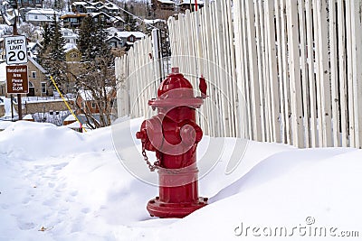 Vibrant red fire hydrant against snow and hill homes at Park City Utah in winter Stock Photo