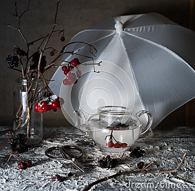 Viburnum branches with berries and snow in a transparent vase, umbrella on wooden table Stock Photo