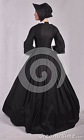 Victorian woman in black ensemble on studio backdrop Stock Photo