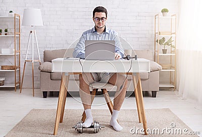 Video call and working from home. Man in glasses, shirt, shorts and socks at workplace, with dumbbell Stock Photo