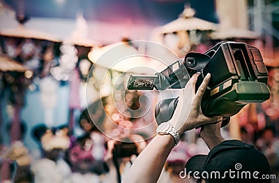 Cameraman lifts the camcorder above his head while filming video Stock Photo