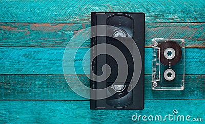 Video cassette, audio cassette on a turquoise wooden table. Retro media technology from the 80s. Copy space. Top view. Stock Photo