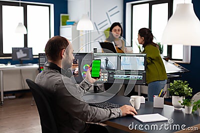 Video editor talking on video call holding smartphone with green screen Stock Photo