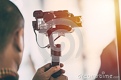 Videographer recording video with mirrorless digital camera on Gimbal Stock Photo