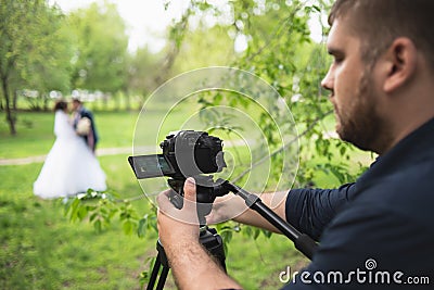 The videographer shootes the marrieds in the garden in the summer Stock Photo