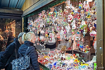 People buy Christmas baubles, toys and souvenirs at traditional Christmas market in front of Editorial Stock Photo