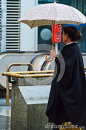 An elderly Austrian woman with a checkered umbrella and a raincoat, Vienna, Austria Editorial Stock Photo