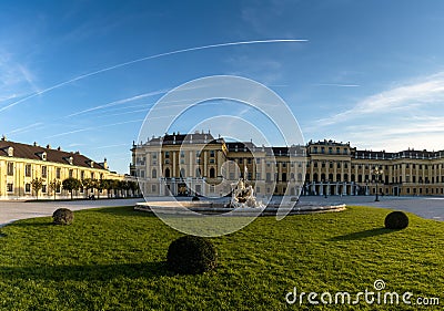 View of the front of the historic Schoenbrunn Palace in Vienna in warm evening light with a fountain in the foreground Editorial Stock Photo