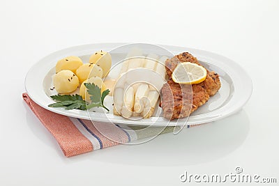 Vienna schnitzel with sauce on asparagus and potatoes in plate Stock Photo