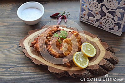 Viennese schnitzel on a wooden board with lemon on a dark background. Meat dish. Stock Photo